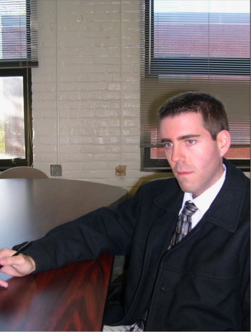 Figure 2: Young Scot with blank expression sits at table holding a pen