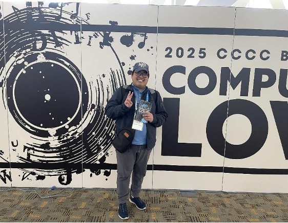 Figure 1: John Paul holding up his badge in from of CCCC sign
