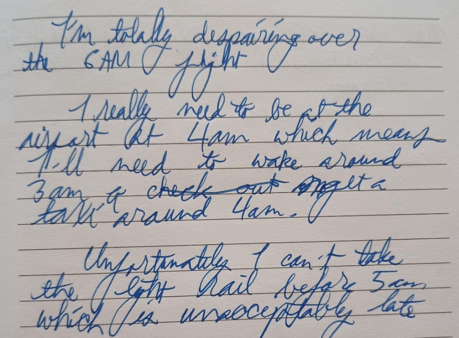 A section of a handwritten journal with the text, 'I'm totally despairing over the 6AM flight 'I really need to be at the airport at 4am which means I'll need to wake around 3am & get a taxi around 4am. 'Unfortunately I can't take the light rail before 5am which is unacceptably late'
