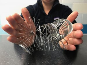 The same two hands holding the same slinky tangled up and twisted.